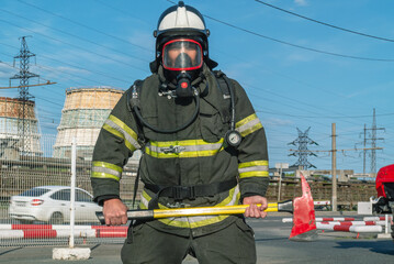 A firefighter in protective clothing and helmet holds an assault axe in his hands. A firefighter on...