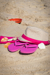 Fototapeta na wymiar Different accessories using for relax on beach. Straw hat, flip flop and towel. Summertime