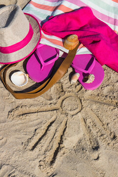Shape of sun and accessories for relax on sand. Straw hat, slippers and towel. Vacation time on beach