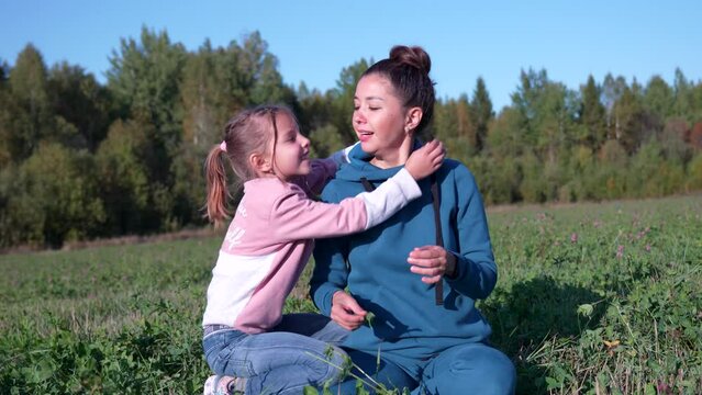 Happy child runs to young mother, daughter hugs her mother in field