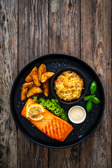 Grilled salmon steak with baked potatoes and sauerkraut served on wooden table 