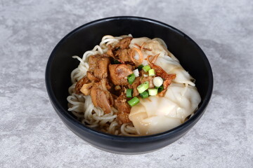noodles topped with boiled egg, spring onions, fried onions, dumplings, lime