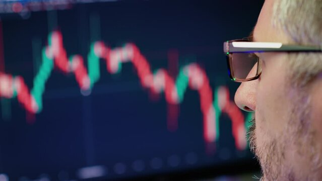 man analyzes a chart of cryptocurrency or stock market looking at the monitor screen, online futures and derivatives trading, data analysis