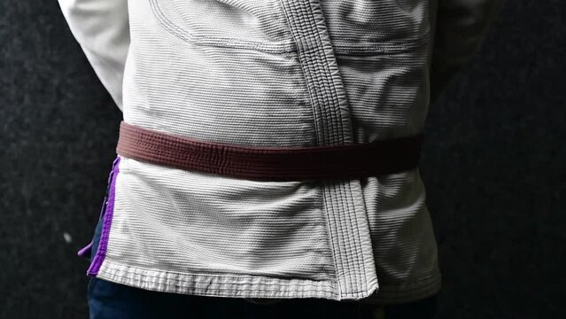 Martial arts  belt tying, brown belt jiujitsu wearing a Gi