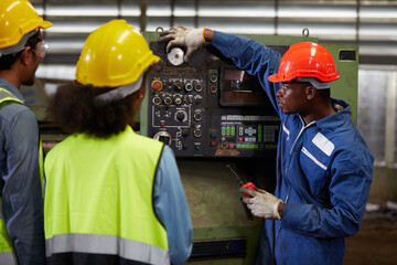male african foreman training and teaching how to use machine control with workers in factory
