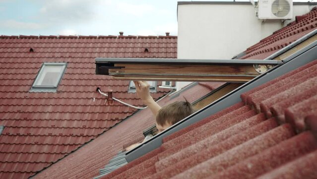 Happiness of a mother and her son as they open attic windows and peer outdoors, symbolizing the essence of family joy, parents with their children, and the excitement of a new home.