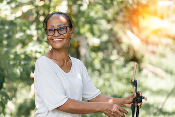 Asian senior woman use smartphone with beautiful view in the garden. Asian woman traveling with the beautiful nature of Thailand.Travel with senior models concept.