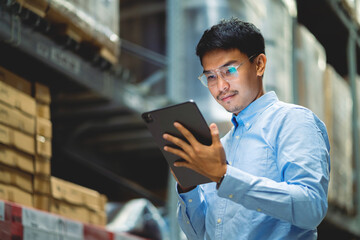 Portrait of Asian Chief Engineer checking product details and supplies on shelf with stock in warehouse background. Logistics warehousing and export concept of logistics business