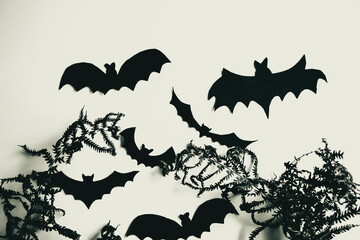 Bats made of paper in dry grass. Halloween crafts - home decorations. In a dried fern, black bats made of paper.