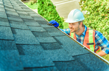 man with hard hat standing on steps inspecting house roof