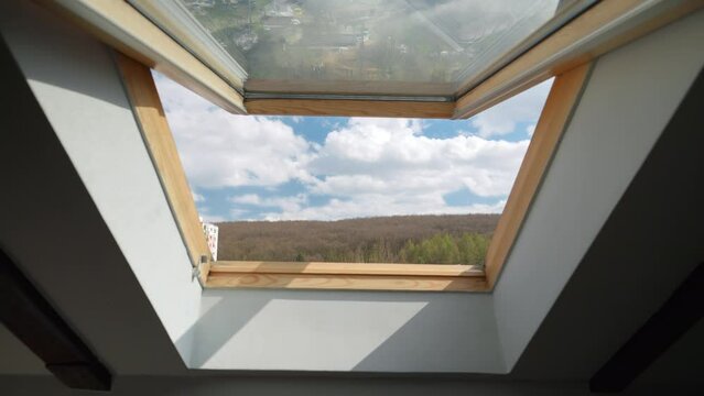 View from the open window at attic on blue sky with clouds.