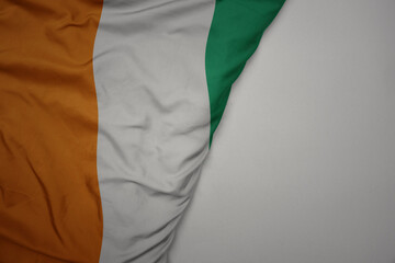 big waving national colorful flag of cote divoire on the gray background.
