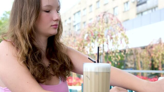 Happy woman drinking ice latte in a park. High quality 4k footage