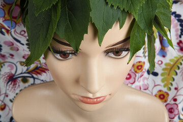 a display mannequin wearing hair of leaves on pink velvet background