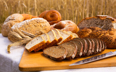 Lot of different flavored bread, wheat, rye, on the table in the field outside