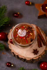 A glass of hot chocolate with cinnamon and spices on the Christmas table. Hot winter drink, vertical photo