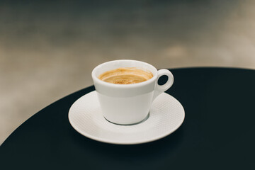 Cup of black coffee on a table in a street cafe.
