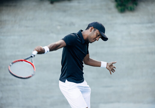 Male tennis player practicing hit outdoors. Professional tennis player spending time on a hard court.