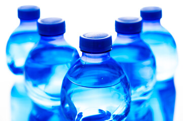 Transparent blue plastic bottles containing water, next to each other. Use and recycling of plastic, environmental protection.