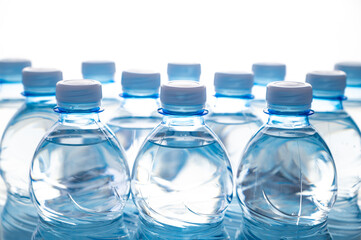 Transparent blue plastic bottles containing water, next to each other. Use and recycling of plastic, environmental protection.