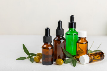 Olive essential oil. Glass bottle with olive oil on a texture table. Olive cosmetic oil. Serum for moisturizing and nourishing skin and hair. Beauty concept. Natural cosmetic. Copy space.spa