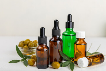 Olive essential oil. Glass bottle with olive oil on a texture table. Olive cosmetic oil. Serum for moisturizing and nourishing skin and hair. Beauty concept. Natural cosmetic. Copy space.spa