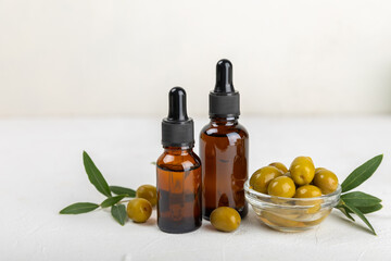 Olive essential oil. Glass bottle with olive oil on a texture table. Olive cosmetic oil. Serum for moisturizing and nourishing skin and hair. Beauty concept. Natural cosmetic. Copy space.spa