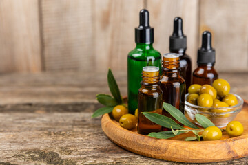 Olive essential oil. Glass bottle with olive oil on a texture table. Olive cosmetic oil. Serum for moisturizing and nourishing skin and hair. Beauty concept. Natural cosmetic. Copy space.spa