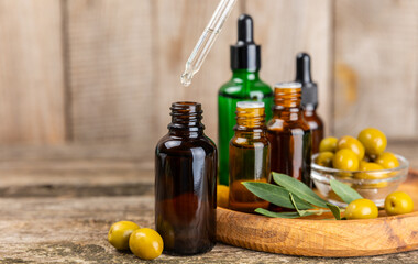 Olive essential oil. Glass bottle with olive oil on a texture table. Olive cosmetic oil. Serum for moisturizing and nourishing skin and hair. Beauty concept. Natural cosmetic. Copy space.spa
