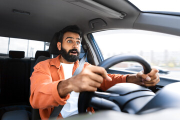 Scared indian man looking at road in shock driving auto