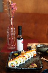 Asian food assortment. California sushi roll placed on ceramic oriental style plates. Soy souce, ginger and chopsticks on sides