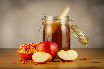 Honey in a jar with apple and pomegranate on wooden table
