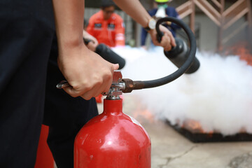 Employees firefighting training, Concept Employees hand using fire extinguisher fighting fire...