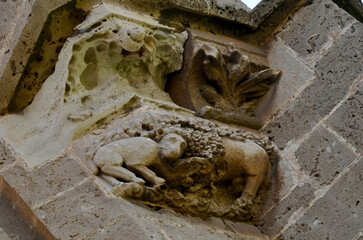 A detailed stone relief carving depicting a lamb-like figure on the ancient exterior wall of the...