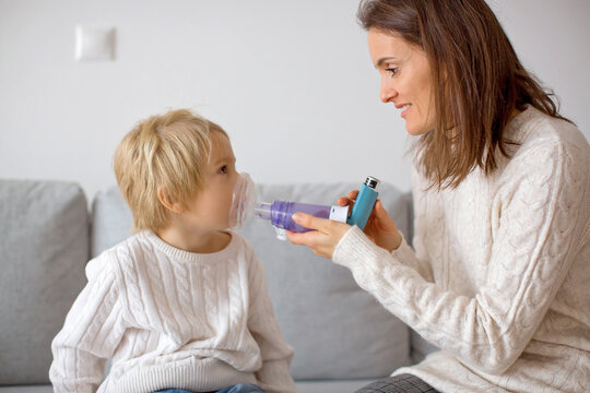 Mother, helping little toddler child with inhaler with spacer