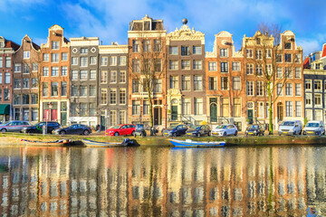 Cityscape on a sunny winter day - view of the houses and the city channel with boats in the historic center of Amsterdam, The Netherlands