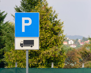 Fototapeta premium Close-up photo of a Truck parking sign on a metal pole with a tree and sky in the background