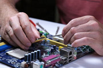 A technician repairs a motherboard in a service center. Computer Repair