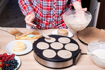 Woman cooking delicious crepe on electric pancake maker in kitchen, closeup