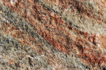 Granite stone surface with roughness and unevenness with red and gray veining for use as an abstract background and texture.