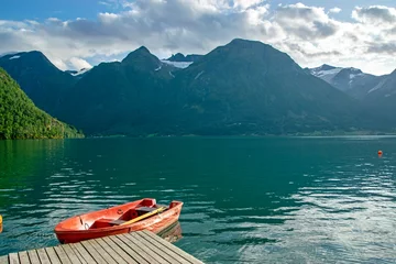 Fotobehang Hjelle, Norway: view of a fjord with montains and glaciers and a red boat in foreground © A. Ciangherotti