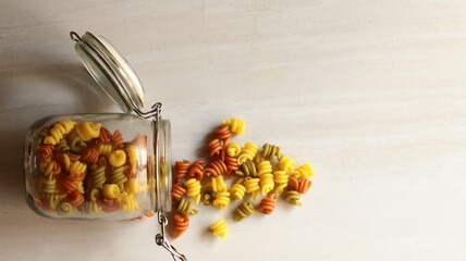 pasta de colores,arroz y legumbres en tarro de cristal sobre fondo gris