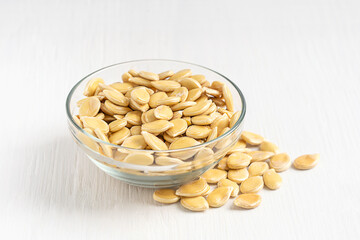 Side view of raw fresh dry edible pumpkin seeds flat and asymmetrically oval, have a white outer...