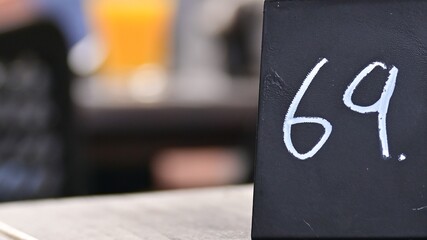 Czarny numerek z białymi cyframi 69 na stoliku restauracji.