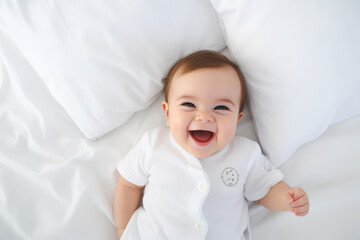 A photo of a baby lying on a white bed sheet - obrazy, fototapety, plakaty