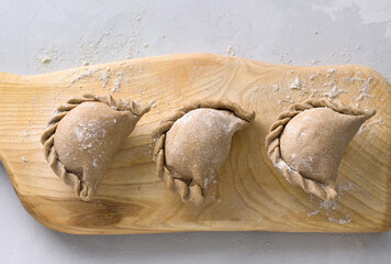 Making pies from rye dough on a wooden board, top view. Cooking stage