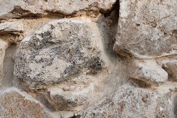 Building background, old wall made of strong large porous stones, close up, selective focus