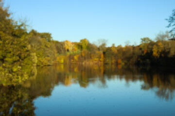 Fototapeta na wymiar Blurred view of beautiful lake and yellow trees on autumn day