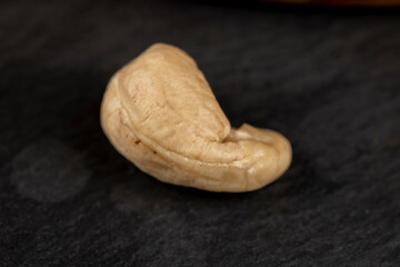 peeled cashew nuts on a black slate board, close-up