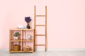 Jug with beautiful lavender flowers, decor and ladder near pink wall in room